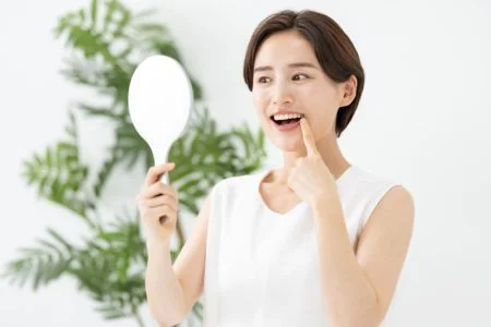 女性が鏡で歯を見ているところ